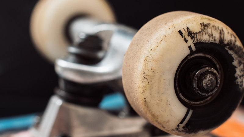 Close-up of worn skateboard wheel and trucks showing setup details