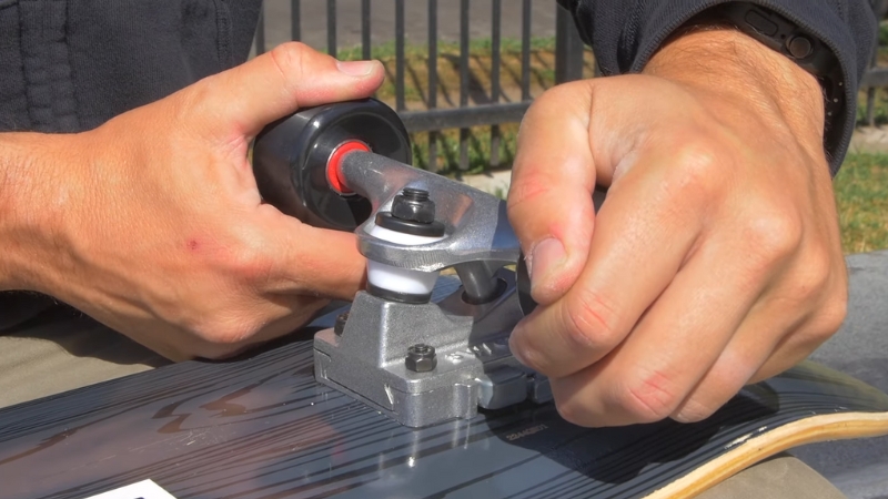 Person using a skate tool to adjust skateboard trucks on a deck