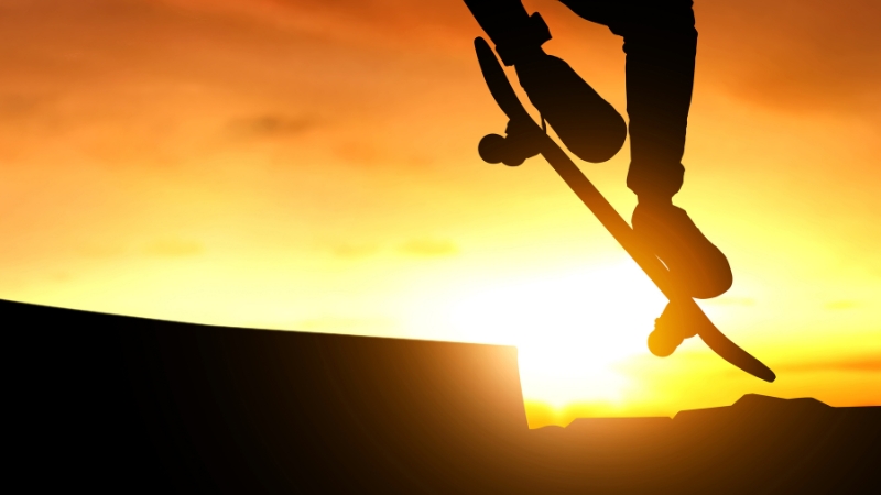 Silhouette of a skateboarder performing a trick at sunset in an outdoor skatepark
