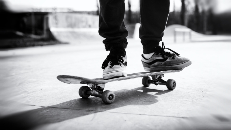 A skater practices balance on a skateboard at a park, showing early skill development